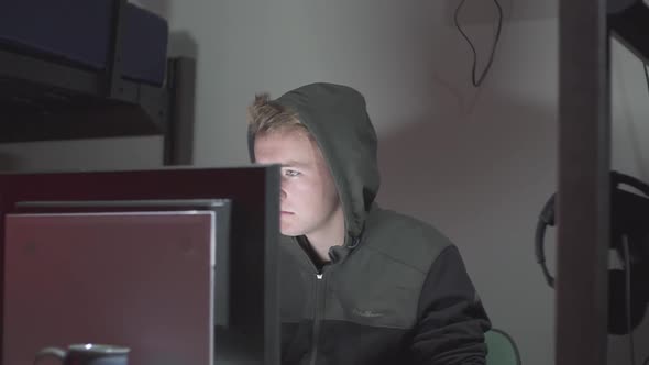 A left to right pan of a hacker at a computer. alt