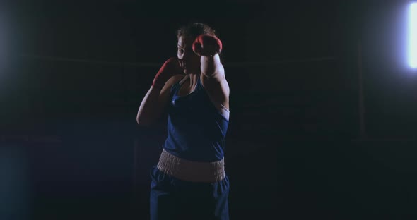 Professional Beautiful Female Boxer Otbryvatyvat Blows Conducting a Fight with a Shadow in a Dark alt
