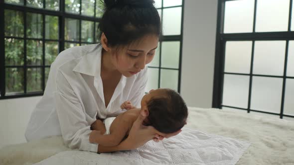 young mother gently holding the baby infant, white color tone and family new born concept