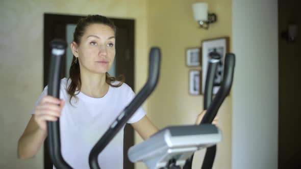 girl goes to ellipsoid, starts the program and starts the workout and finishes alt