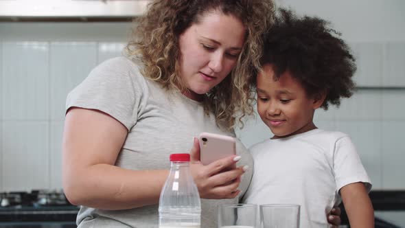 White Mother and Her Mixed Black Daughter Looking at the Phone Screen alt