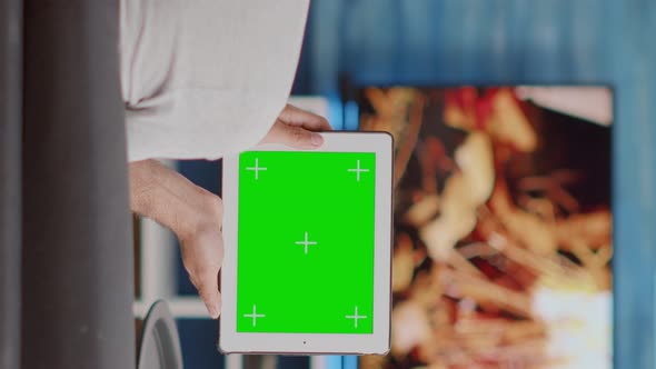 Back View of Man Holding Digital Tablet with Green Screen Watching Social Media Video Content alt