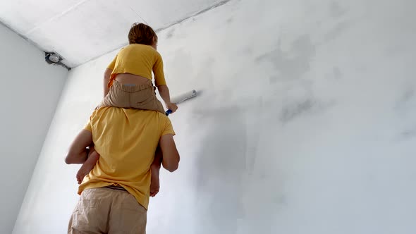 A Father and Son Both Wearing a Yellow Tshirt Paint the Wall Using a Roller Painter alt