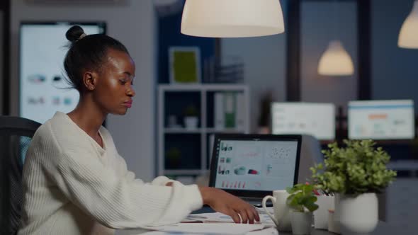 Black Manager Analysing Graphics and Financial Statistics From Documents alt