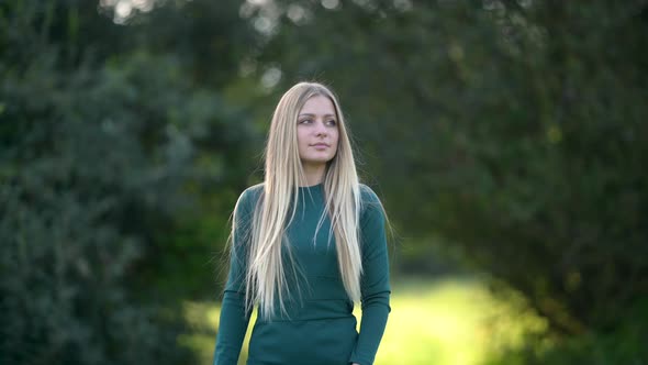 Portrait of an attractive blonde woman walking in the park on a sunny day alt