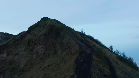 Ascending Aerial Shot Flying Past a Tropical Hill Top of Mount Batur in the Dark alt