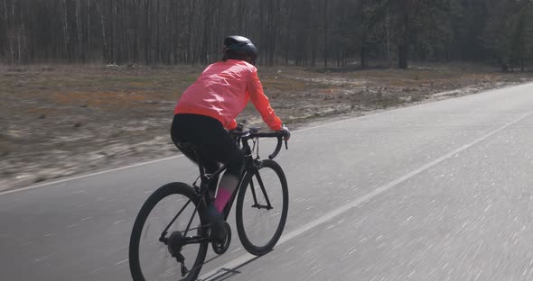 Woman cycling. Female pedaling on bike. Cyclist riding on bicycle alone on empty road. alt