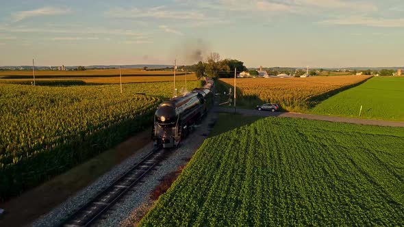 Aerial View of a Steam Engine Puffing Smoke and Steam with Passenger Coaches Traveling alt