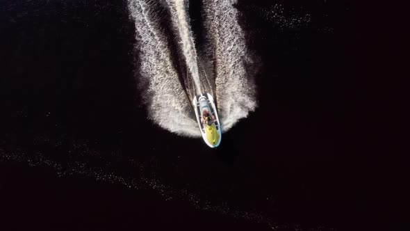 Mom and Daughter Ride Along the River on a Personal Watercraft. Aerial View alt
