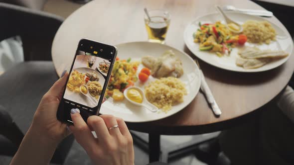 Woman Blogger Takes Pictures of Her Food in a Cafe Using Mobile Phone. alt