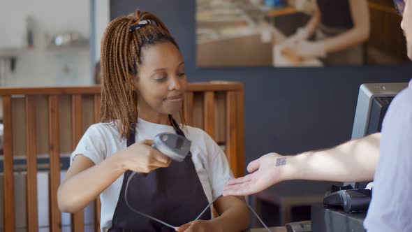 African Woman Waitress Scanning Qr-code on Customer Hand for Online Payment in Cafe alt