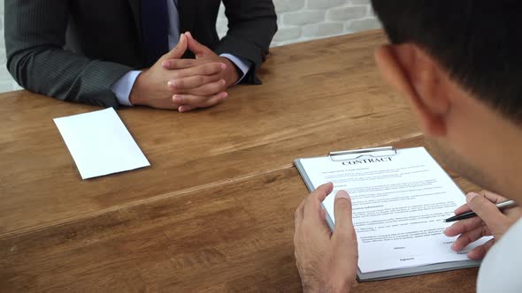 Businessman giving contract paper to his partner to sign on the table