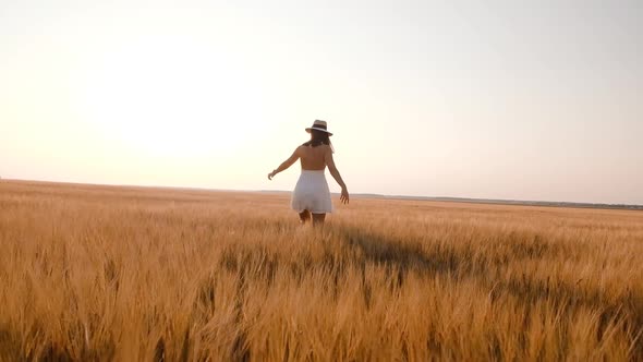 Happy Free Young Woman Dancing and Spinning Around in Slow Motion Across Field Touching Ears of alt