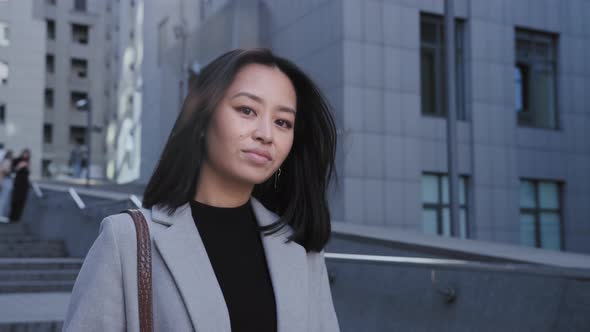European Asian Woman Looking at Camera and Smiling in the City alt