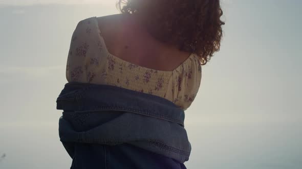 Unknown Girl Standing Backwards on Beach Enjoying Bright Evening Sunlight alt