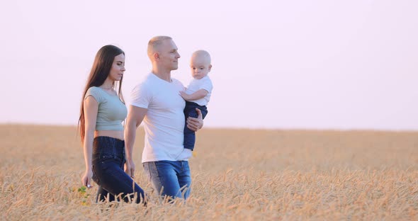 Happy Family Walking in a Field of Wheat in the Sun at Sunset alt