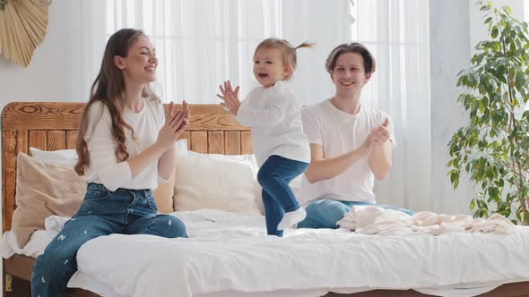 Happy Family Young Parents with Baby Little Daughter Infant Sit on Bed Small Girl Toddler Kid alt