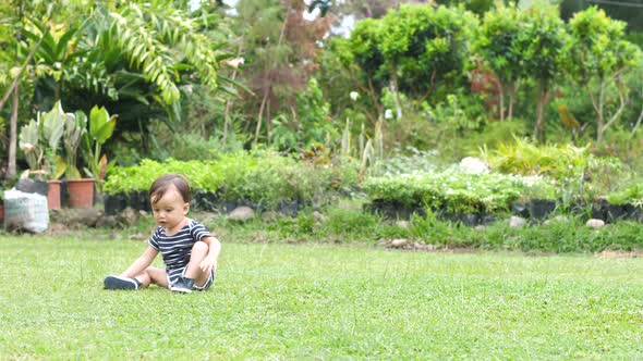 Adorable Little Baby Boy Walking on His Own on the Grass in Tropical Garden Background