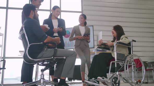 A disabled company employee is able to work happily with colleagues in the office. alt