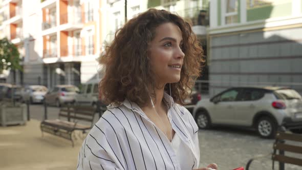 Beautiful Hispanic Girl Using an App on Her Mobile Phone While Walking Outdoors