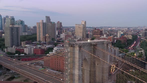 An aerial view of the Brooklyn Bridge at sunrise. The camera orbit the American flag on the bridge's alt
