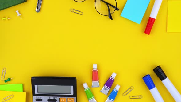 Colorful stationery and office supplies on yellow background with copy space in the middle
