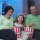 Funny Elder Family and Little Kid Granddaughter Sits on Sofa and Watching TV Eating Popcorn - VideoHive Item for Sale