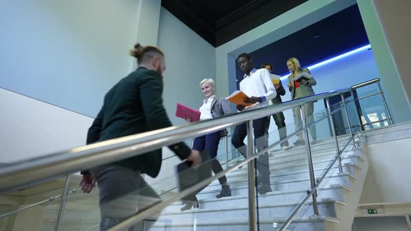 Bottom Angle View Serious Busy People Walking Upstairs and Downstairs in Office Indoors Talking alt