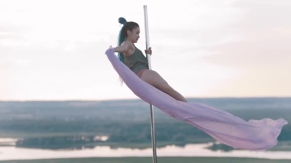 Pole Dance Outdoors - Woman with Long Blue Braids Spinning on the Pole with Pink Veil alt