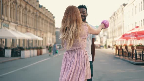 Young Happy Woman Leads Her Boyfriend's Hand Along City Street alt
