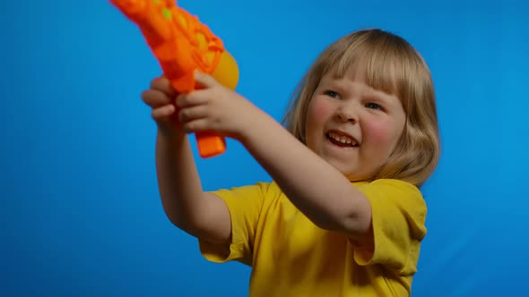 Little Cute Girl in a Yellow Tshirt with an Orange Water Gun in the Studio alt