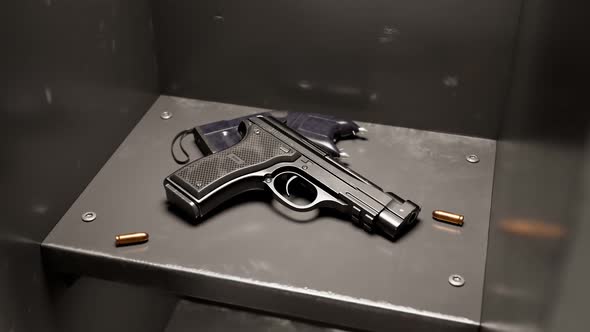 Handgun and stun gun on the shelves of a metal grey locker in a school hallway. alt