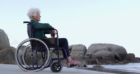 Woman sitting on wheelchair at beach 4k