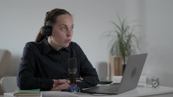 Young woman freelancer speaks into the microphone and records  Podcast alt