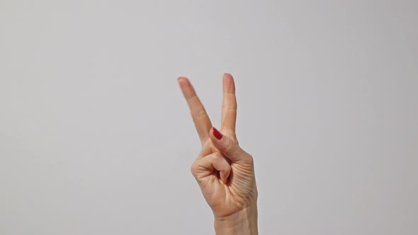 Woman raising two fingers up and showing peace or victory symbol or letter V alt