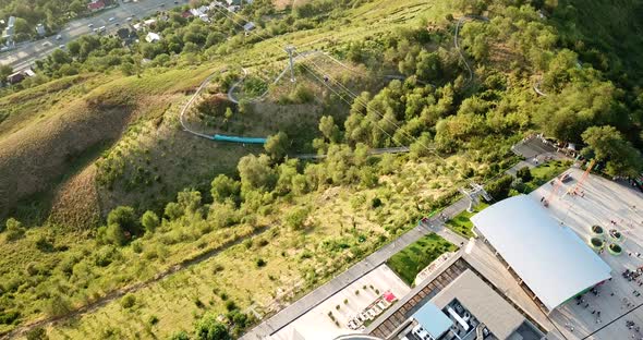 Green hill Kok-Tobe. View of buildings, restaurants, Ferris wheel, stage and green hills.  alt