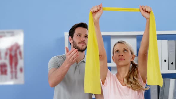 Physiotherapist training female patient with exercise band alt