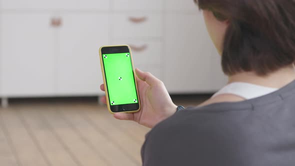 Young Woman Scrolls Green Screen Smartphone