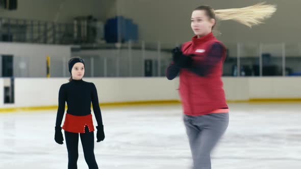 Figure skating girl circling after her trainer on ice