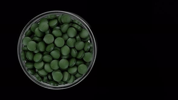Green pills on black background. superfoods Spirulina, chlorella supplement green pills alt