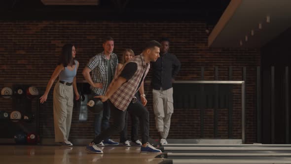 A Young Caucasian Man Makes the Final Throw with a Bowling Ball and Wins the Game with the Support alt