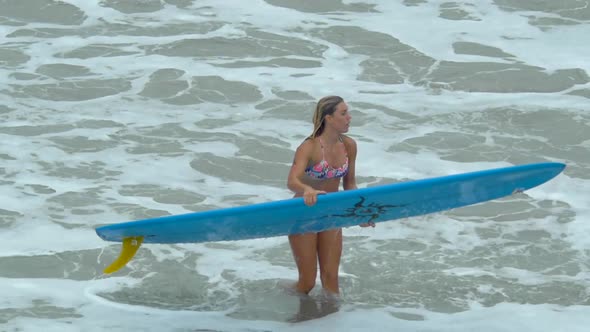 A young woman surfing in a bikini on a longboard surfboard. alt
