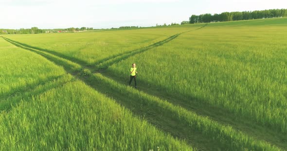 Sporty Child Runs Through a Green Wheat Field. Evening Sport Training Exercises at Rural Meadow. A alt
