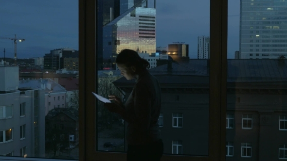 Woman Typing In Tablet By The Window alt