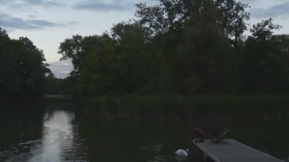 Man is Sitting on Wooden Pier Stretched His Hand alt