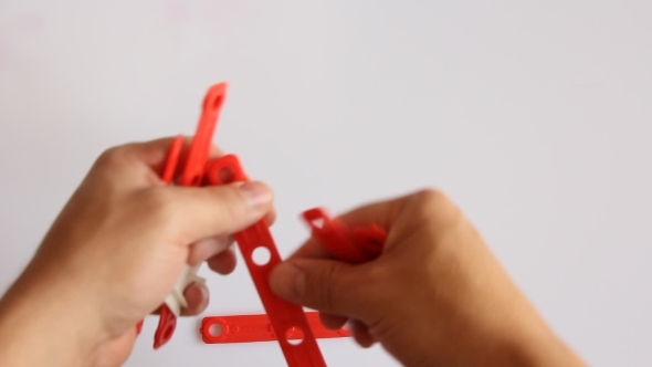 Human Hand Builds Red House On White Background alt