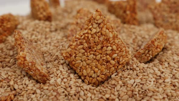 Rotating view of sesame seeds stick placed over heap of sesame seeds alt