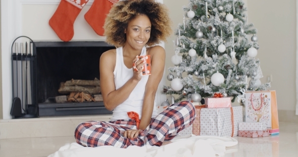 Smiling Young Woman Enjoying a Cup Of Xmas Coffee alt