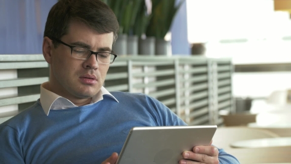 Young Businessman Working On Tablet PC In Cafe alt