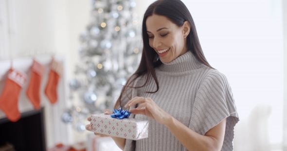 Smiling Young Woman Opening a Christmas Present alt